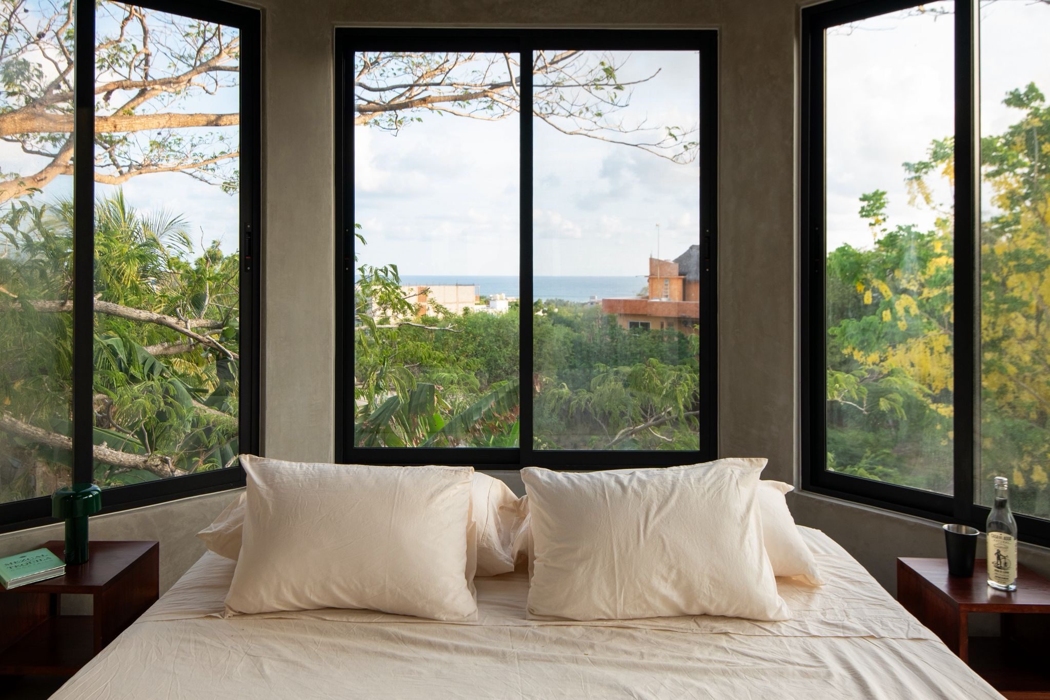 Ocean-facing bed at Brutal Verde looking out through the trees to the sea