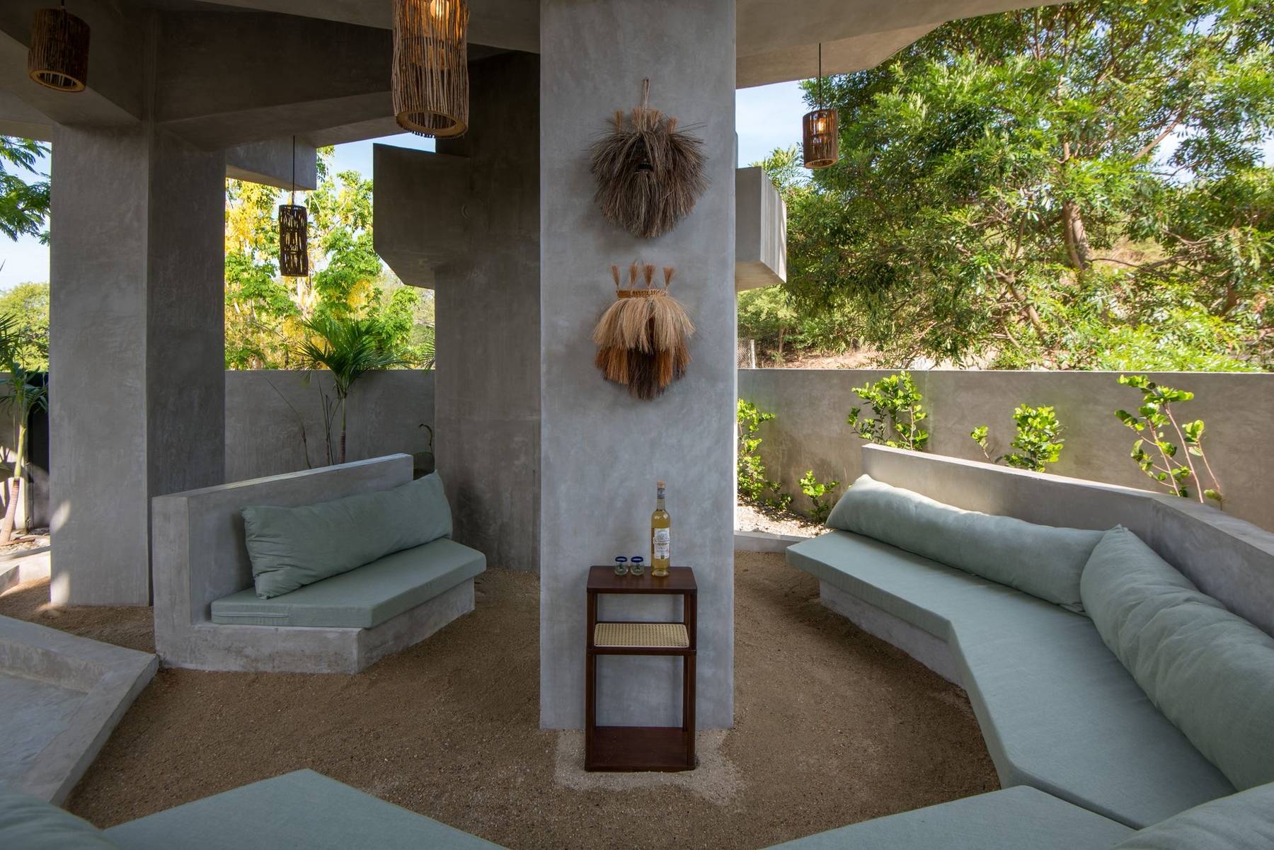 Sunken concrete lounge with soft green cushions open to the garden